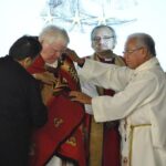 Former indigenous ministries co-ordinators Donna Bomberry and The Rev. Canon Laverne Jacobs wrap “The Evening Star” Pendleton blanket over Archbishop Michael Peers as Bishops Adam Halkett and Lydia Mamakwa look on. Photo: Marites N. Sison